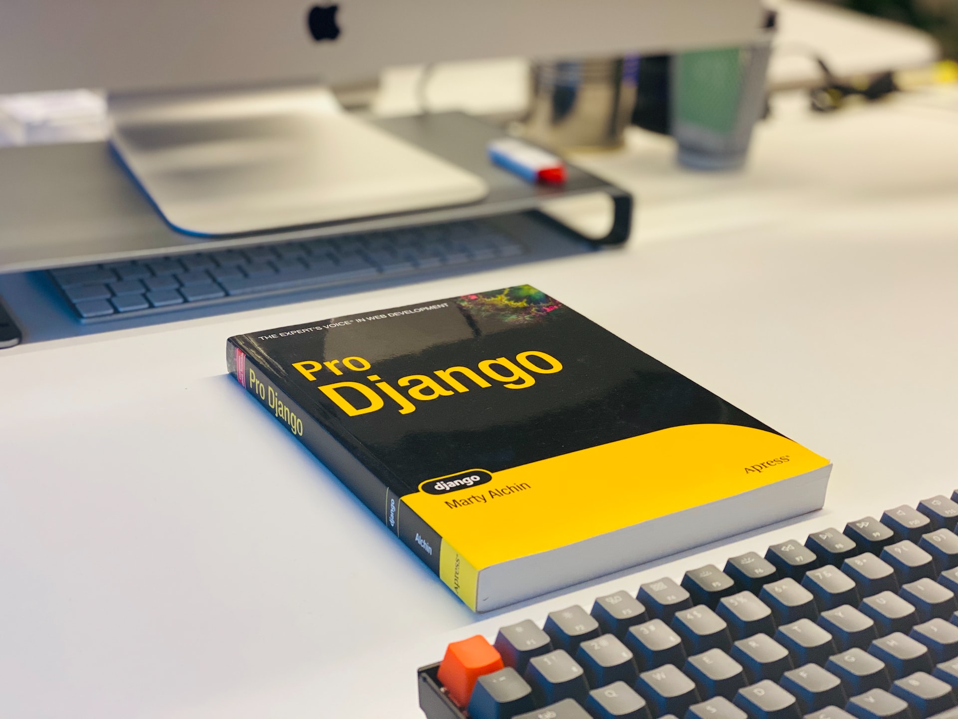 photo of a &#34;Pro Django&#34; book on a desk between a computer monitor and keyboard