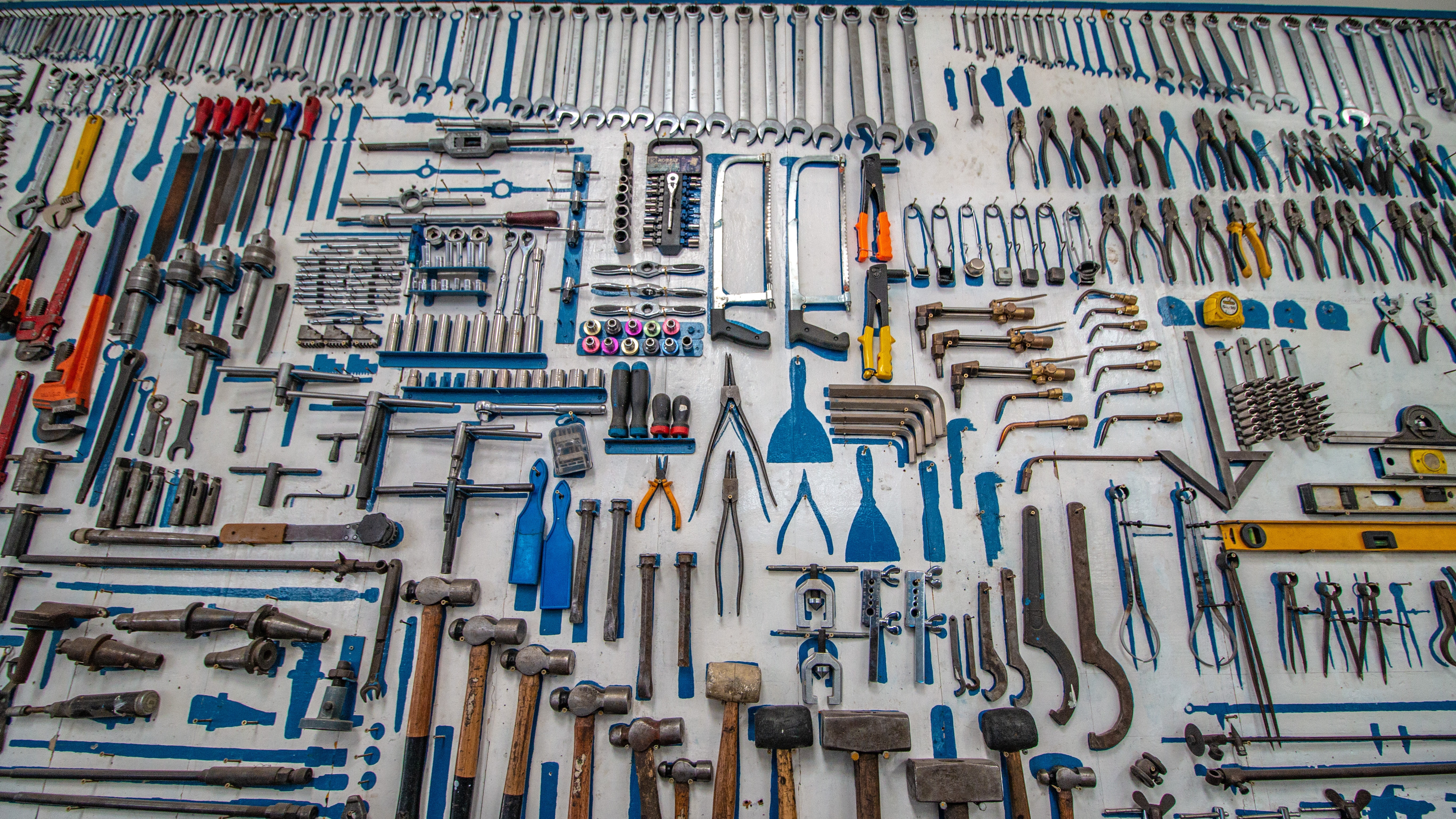 a wall full of carefully organized tools including wrenches, hammers, saws
